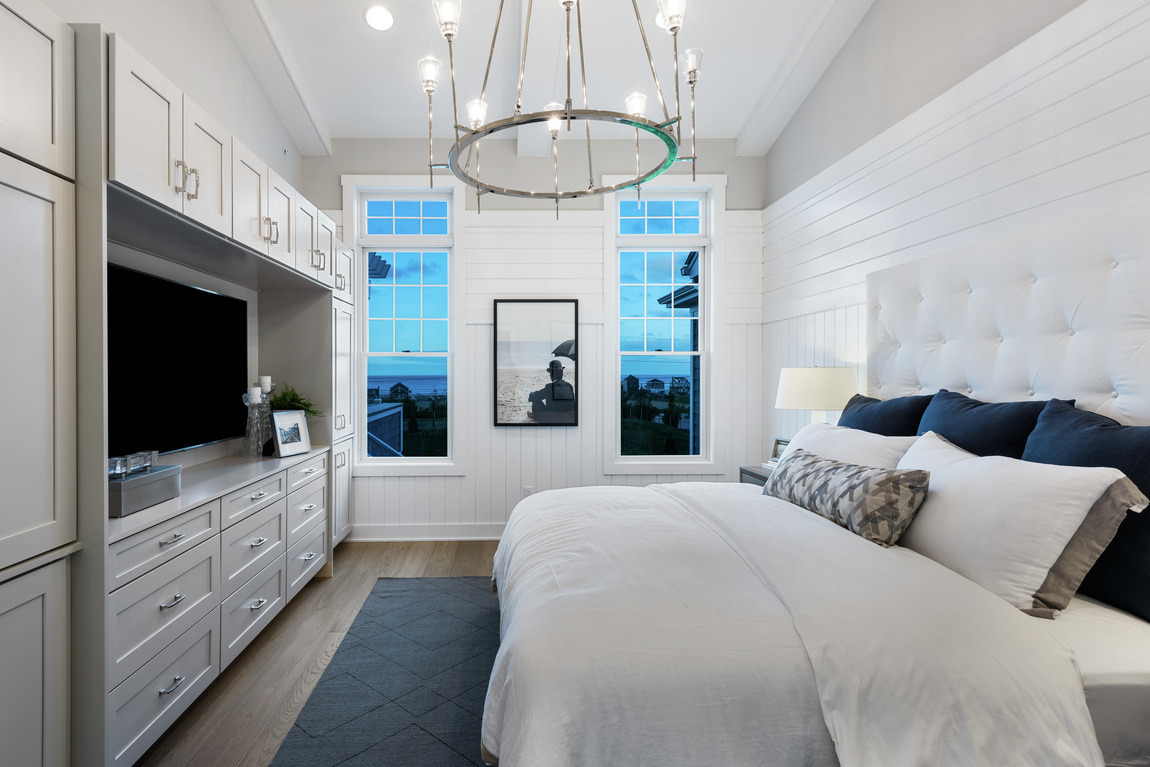 A luxury bedroom with white shiplap walls and white cabinets.