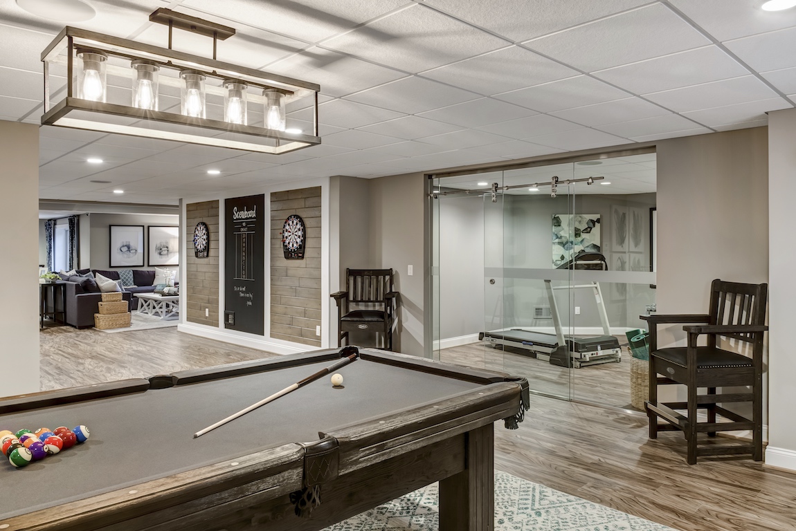 Modern glass barn door separating a home gym in a finished basement. 