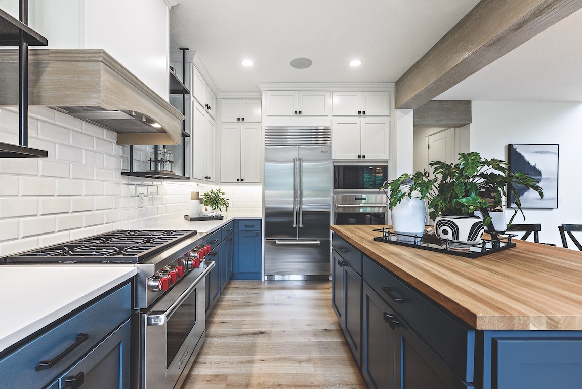 A modern luxury kitchen with blue cabinets and a blue island in a new construction home. 