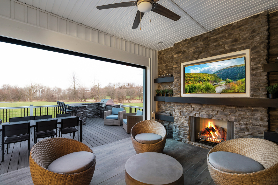 A patio with a TV, and seats overlooking an open field.