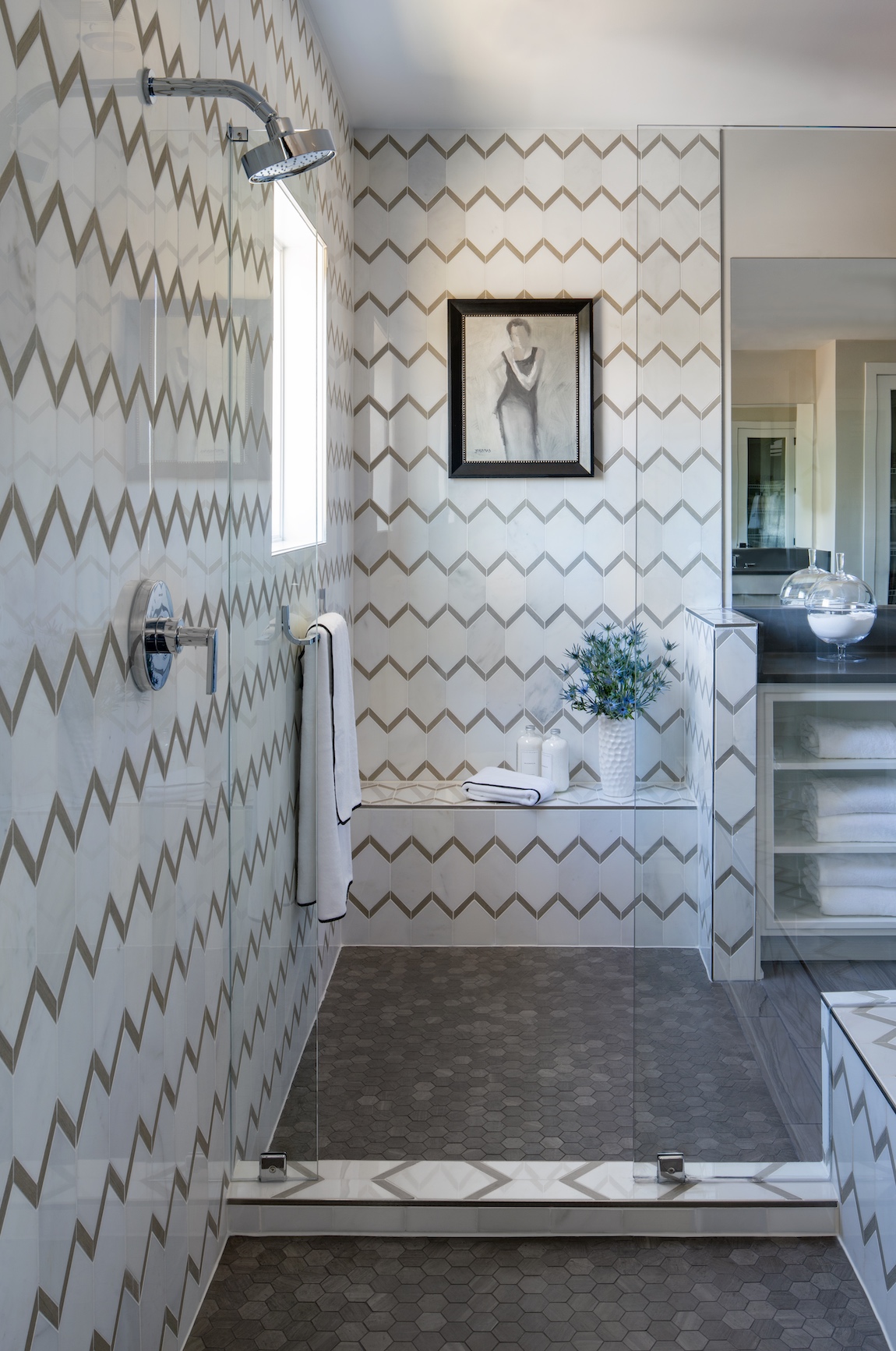 Walk-in shower a seat and a patterned tile.