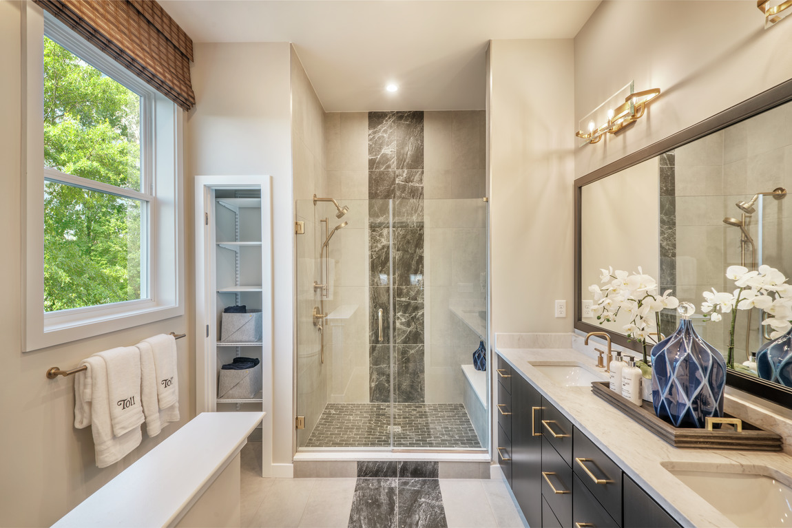 Luxury primary bathroom with gold accents and tiles floor and walls.