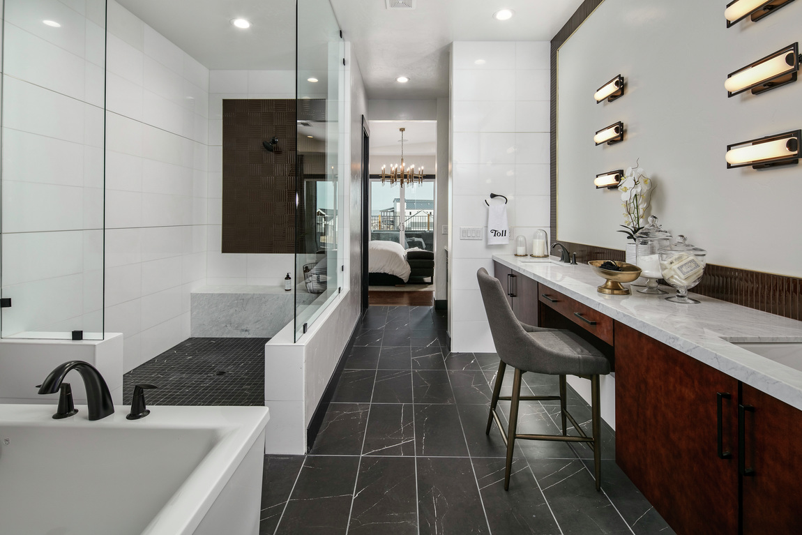 A modern bathroom with a long walk-in shower with a black tile floor.