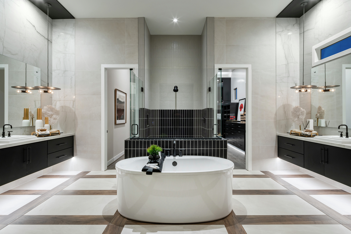 Large luxury primary bathroom with dual sinks, a freestanding bathtub and black accent tiles.