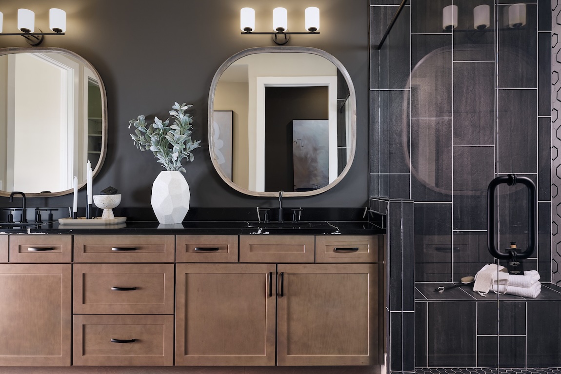 primary bathroom with black tiles and dual sink vanities