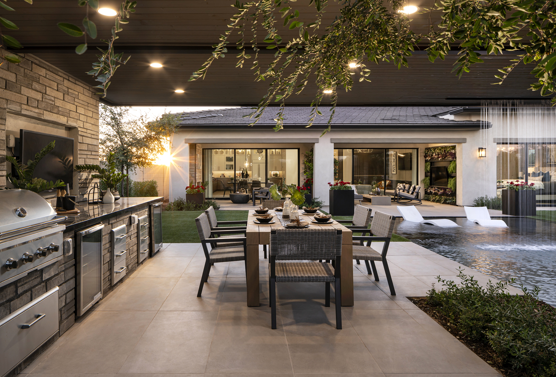 Stunning backyard design with outdoor kitchen, pool, and green space