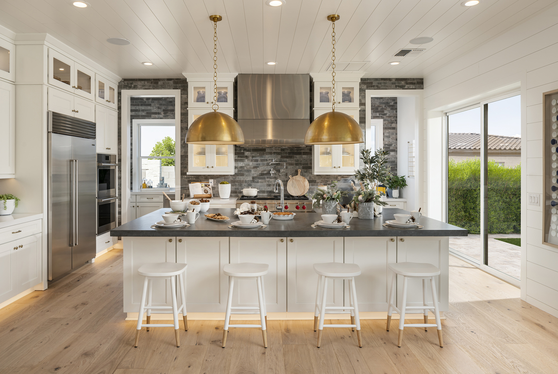Luxe airy kitchen design with accent lighting with baked goods on island