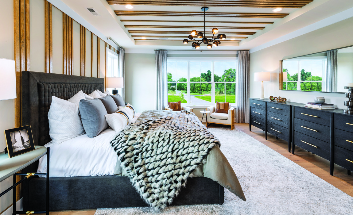 Primary bedroom with accent ceiling and wall, black headboard and chest of drawers with window view to outside greenery