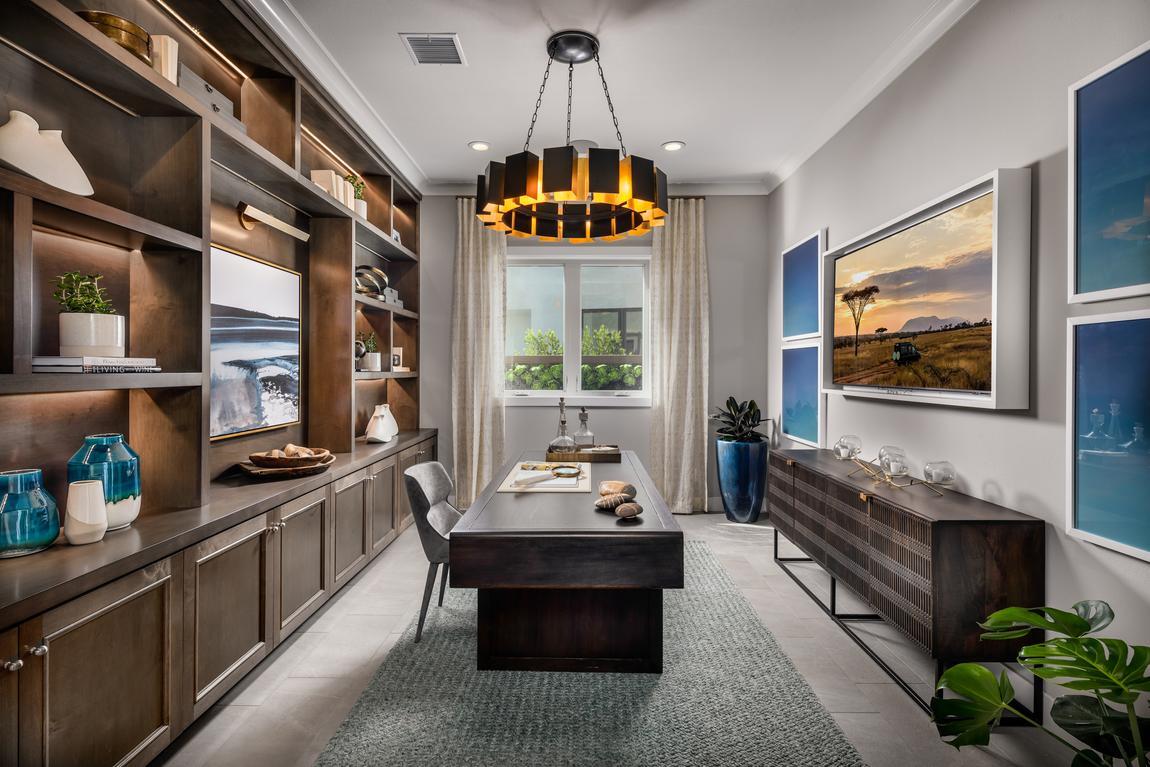 Home office with dark brown floor to ceiling built-in shelving and cylinder light fixture with blue framed paintings