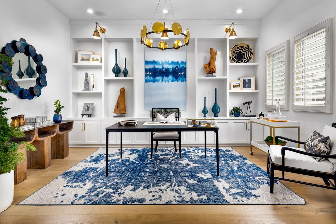 Home office with black table, bar cart, gold and metal light fixtures, and blue patterned carpet