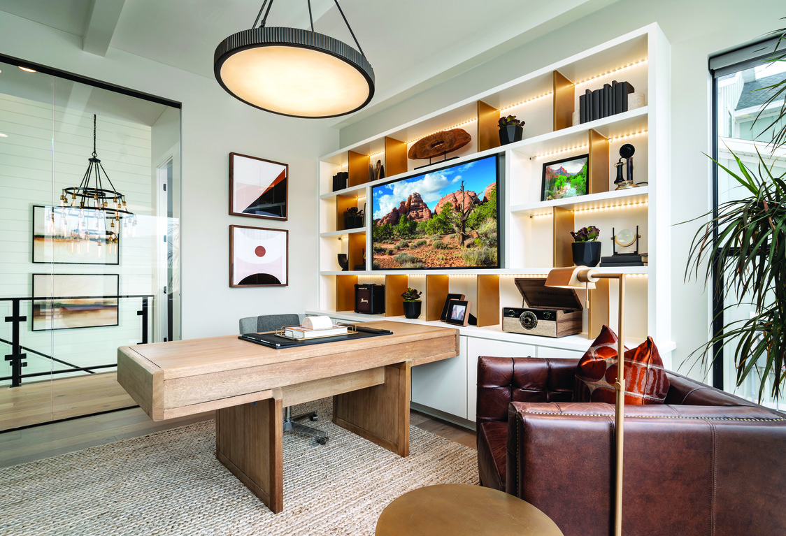 Home office with leather arm chair, floor-to-ceiling built in shelving and recess lighting