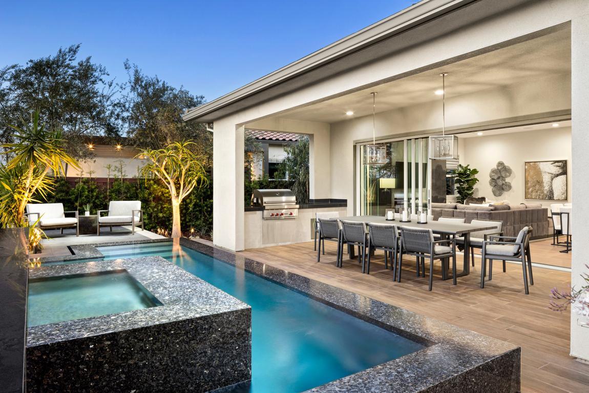 Indoor-outdoor open concept patio doors optimizing space from the living room, to the covered patio, and the luxurious pool beyond