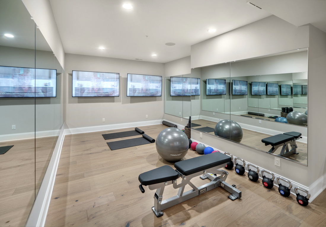 home gym with TVs and mirror wall