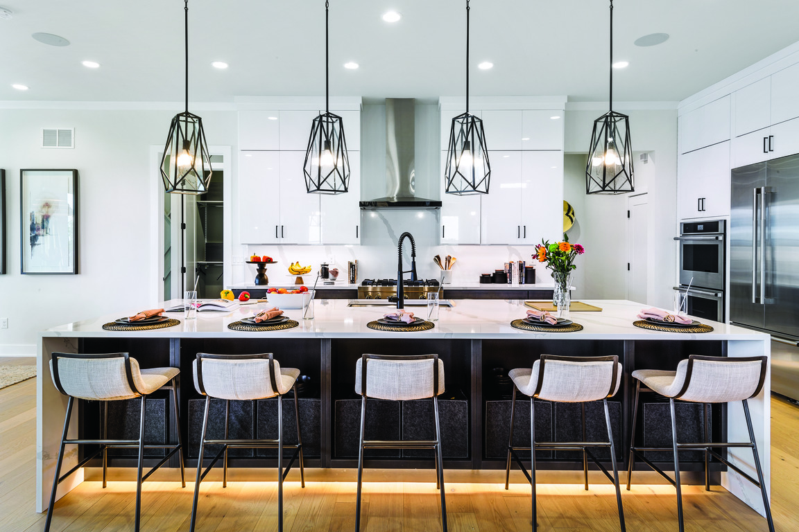 Kitchen island with pendants, black island with toe kick lighting and white stools