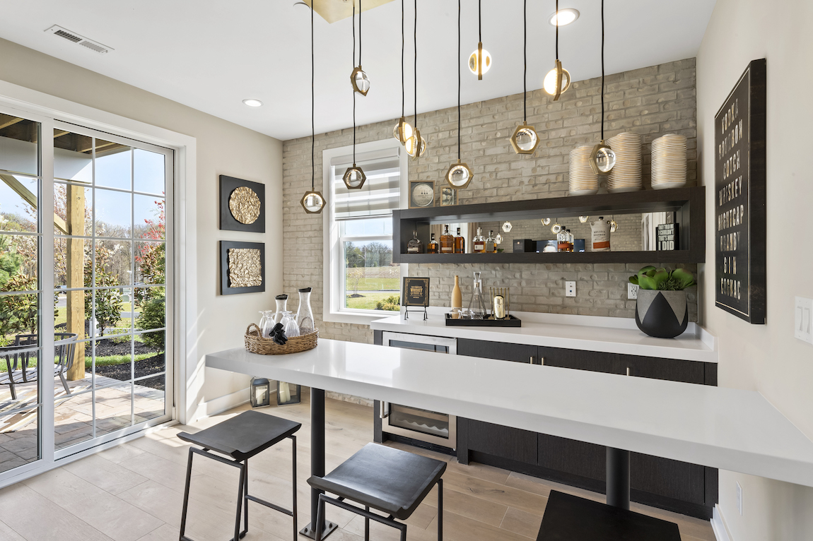 Bar with white countertops, island, octagonal pendant lighting and stone accent wall