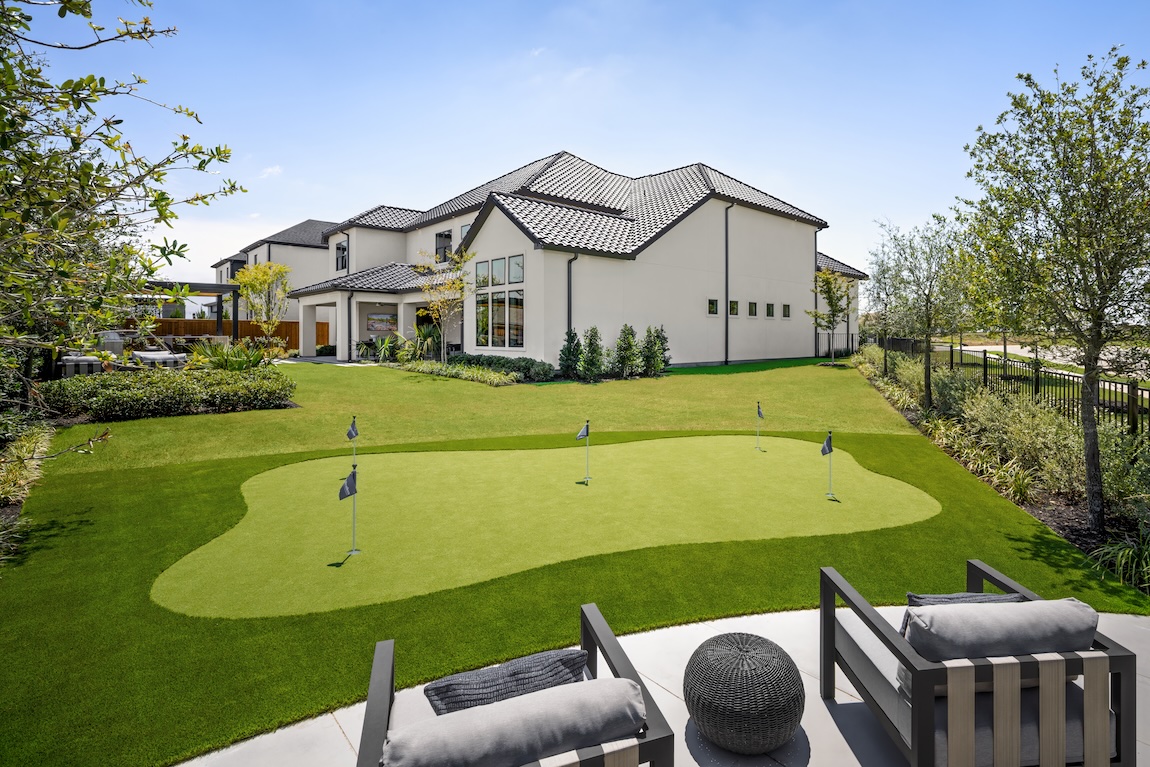 luxury backyard golf with seating and views of the home