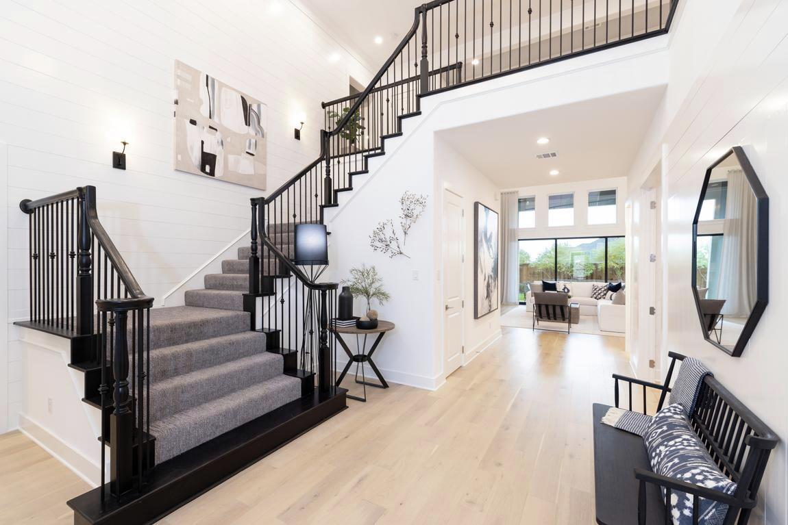 light, airy foyer featuring staircase with gray carpet overlay