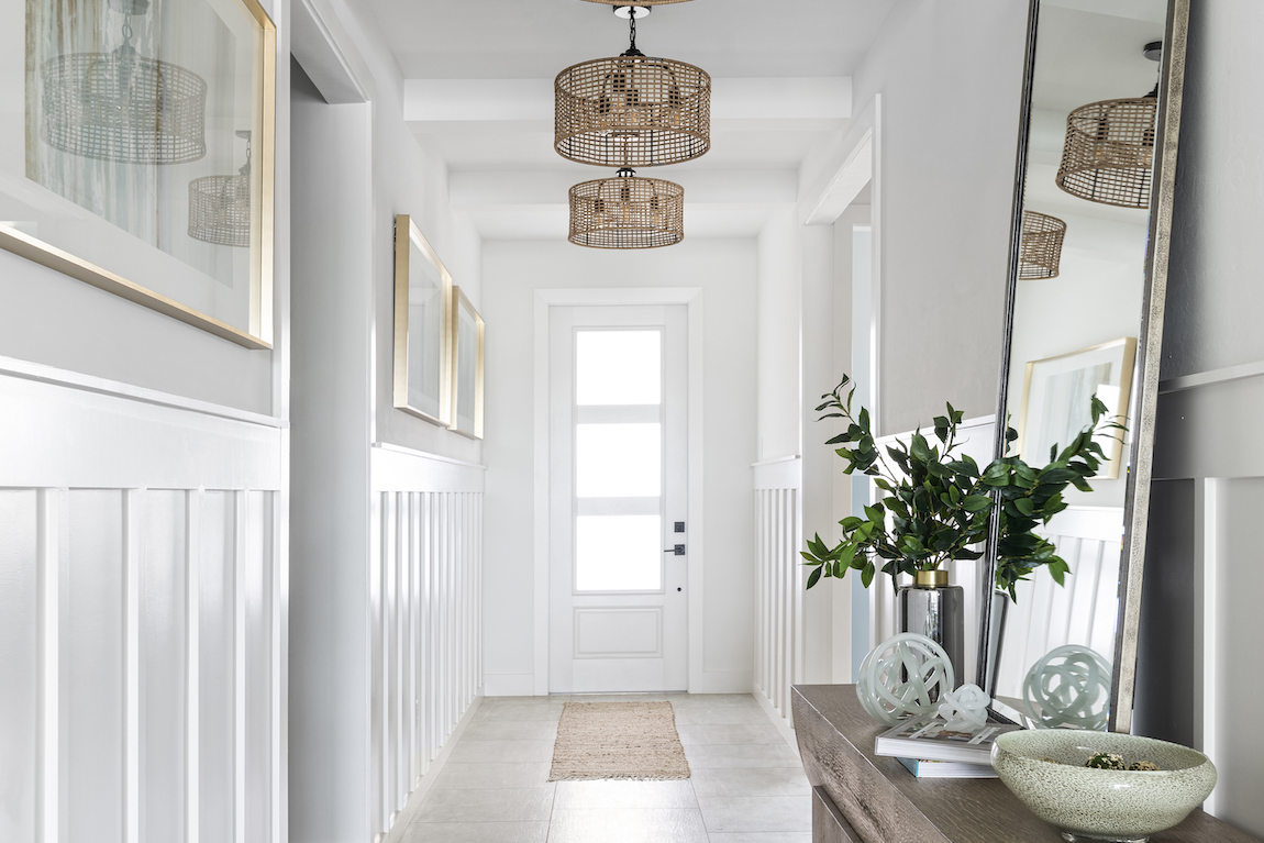 Subtle, elegant foyer design elevated by pendant lighting throughout the hallway