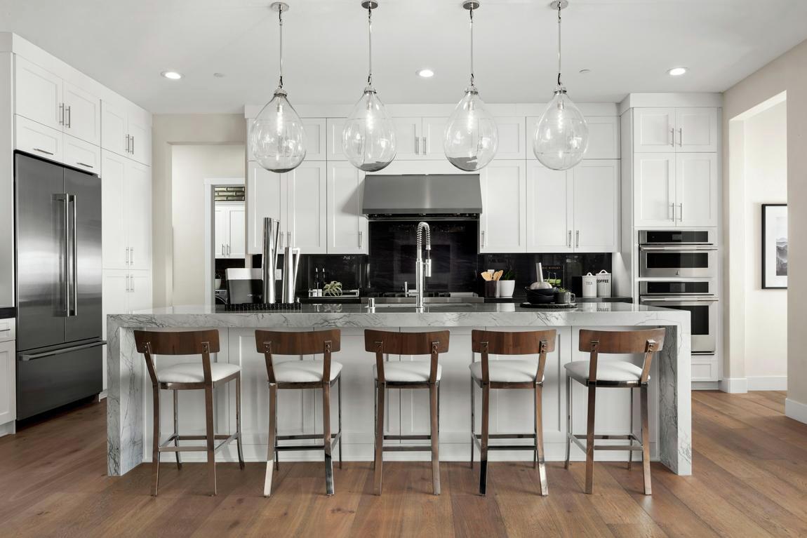 Contemporary kitchen design featuring white cabinetry and oversized pendant lighting