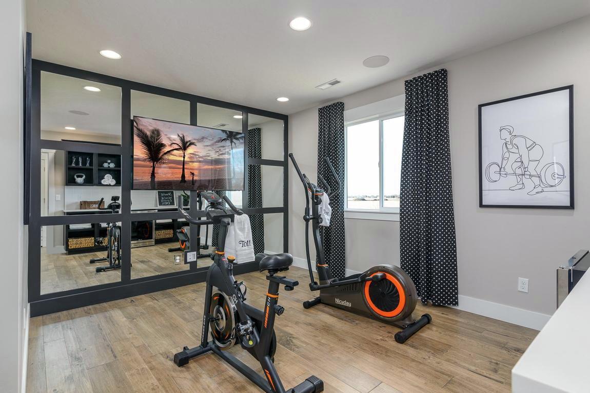 Home gym with workout machines, wood flooring, and wall mirror