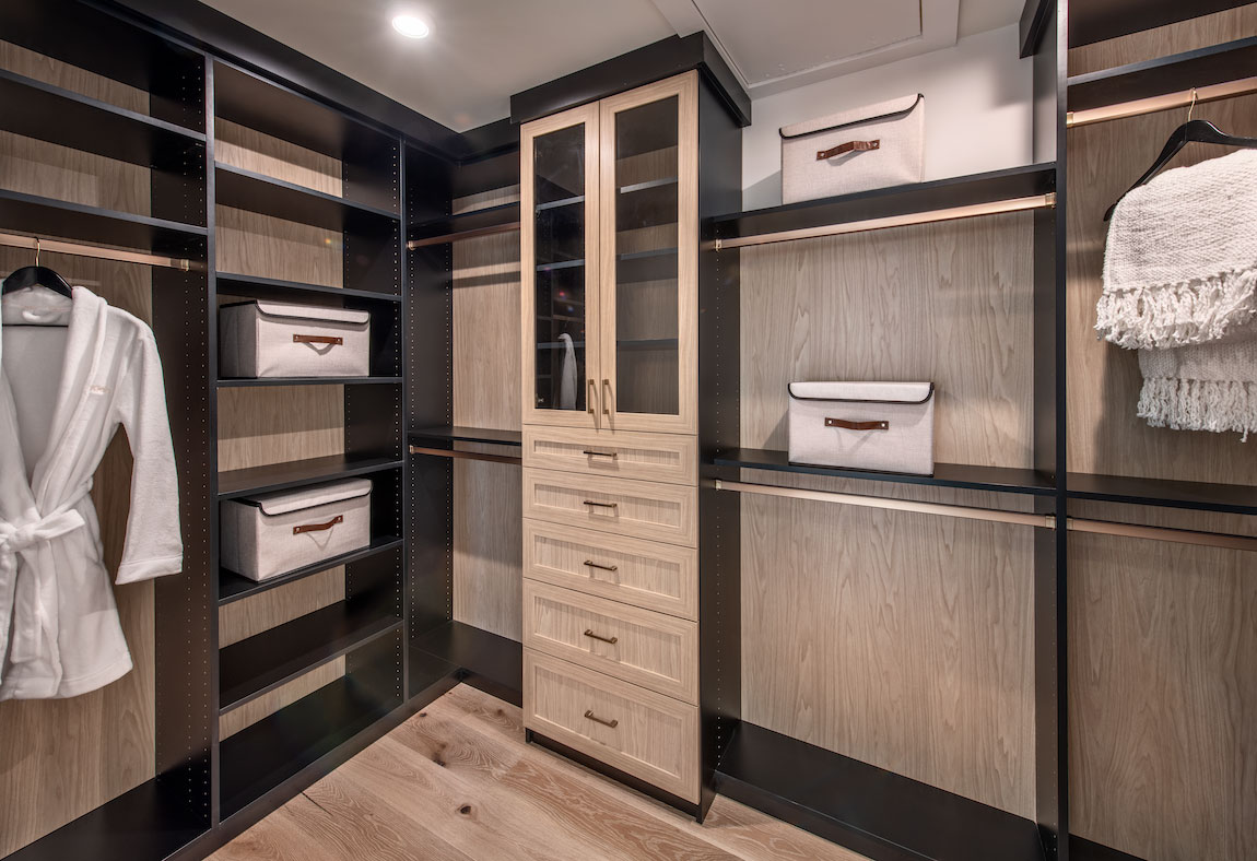 Two-toned black and brown walk-in closet with shelving and storage areas. 