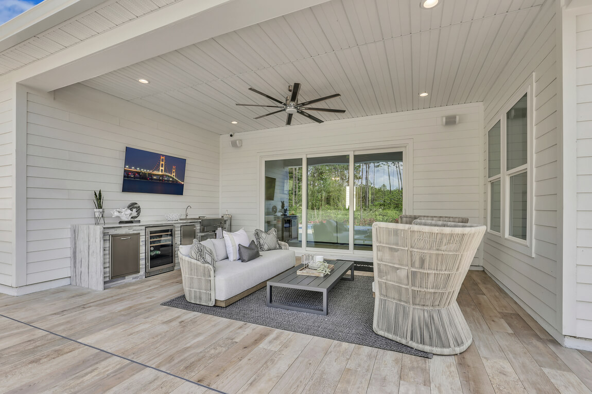 White outdoor covered patio with couch seating area and minibar