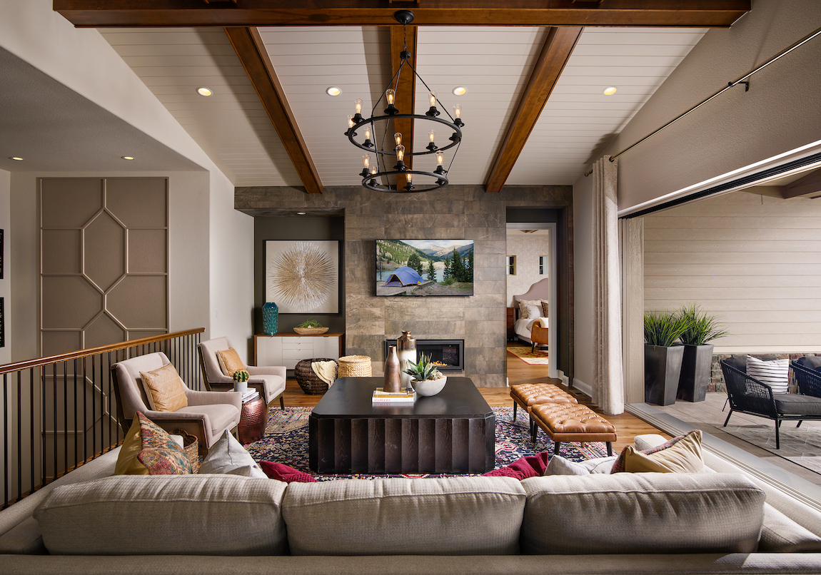 Living room with wood beams, indoor outdoor living space and two-tiered chandelier. 
