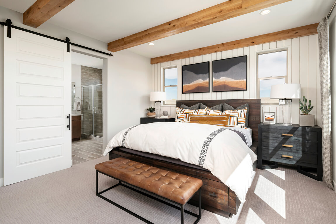 Rustic bedroom design highlighted by barn door, wood beam ceiling, and shiplap wall