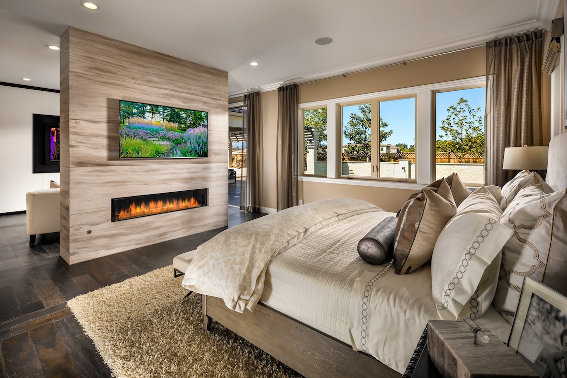 Primary bedroom with double-sided fireplace and tv above mantel