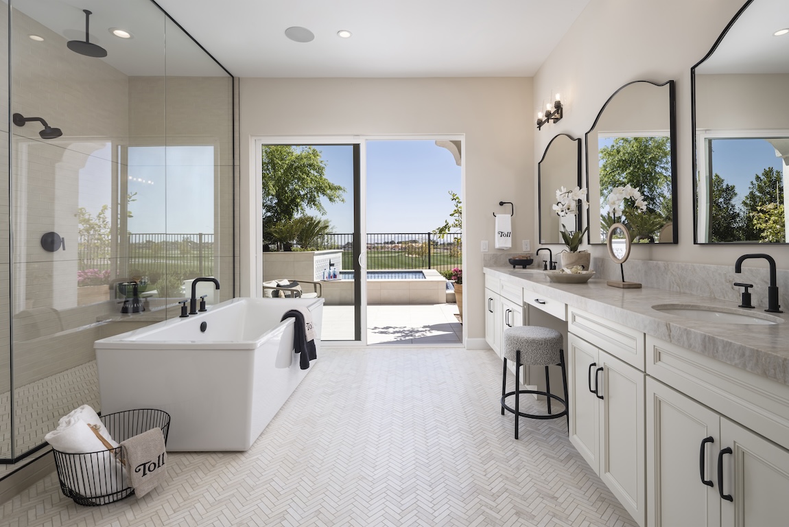 Luxury bathroom design with dual vanity, makeup area, bathtub, shower, and access to outdoor pool area. 