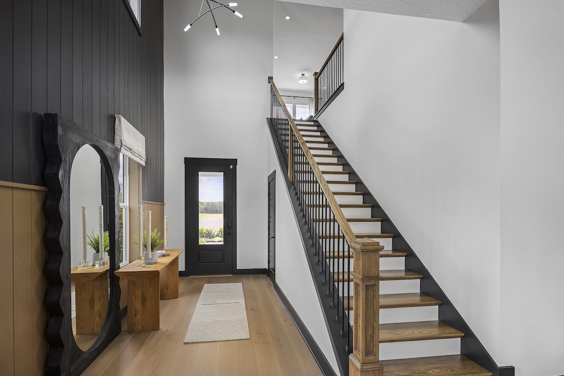 modern entryway with black accent wall and wooden staircase