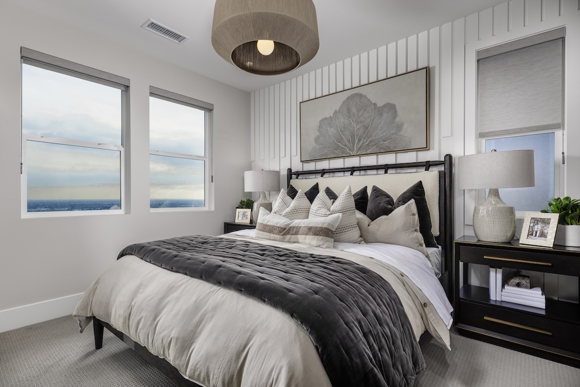 Secondary contemporary bedroom design with white accent wall and sweeping view of surrounding landscape
