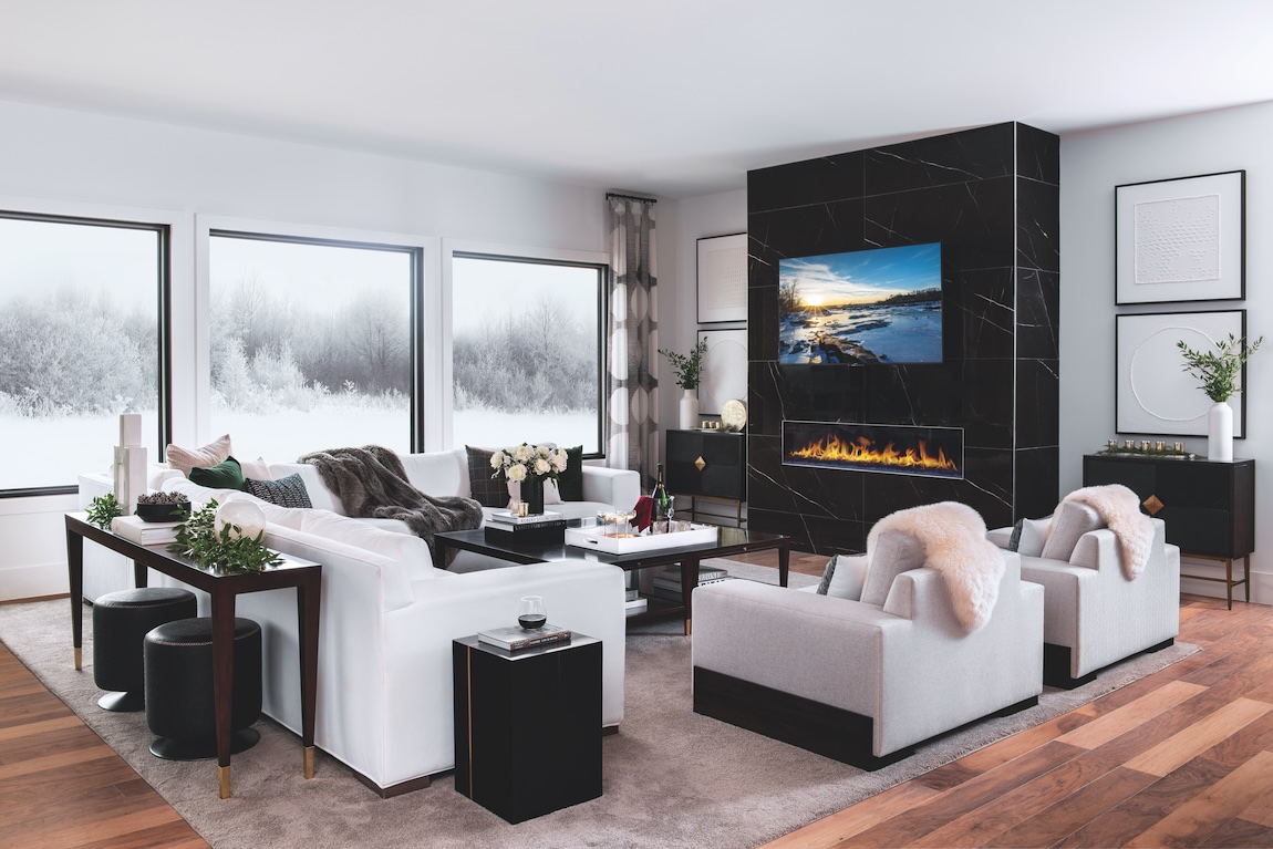 Cozy great room with black accent fireplace wall and snow outside windows