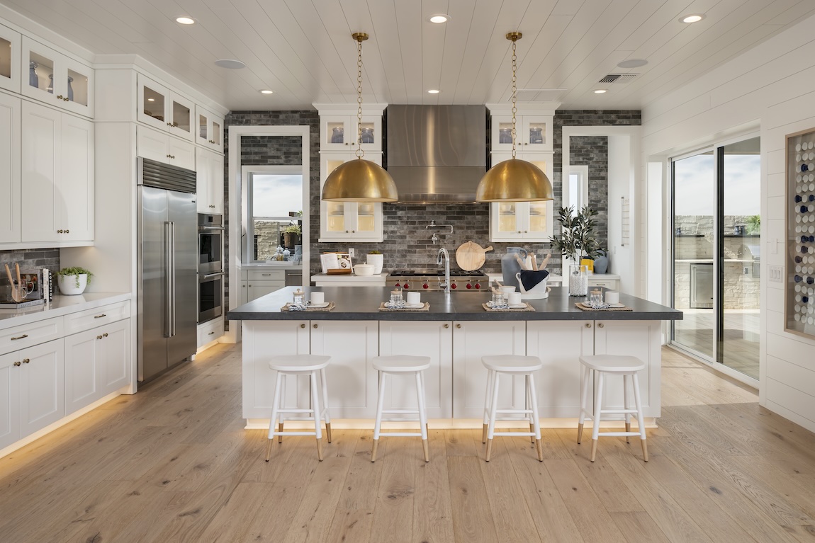Modern kitchen design featuring gold pendant island lighting and accent toe-kick lighting