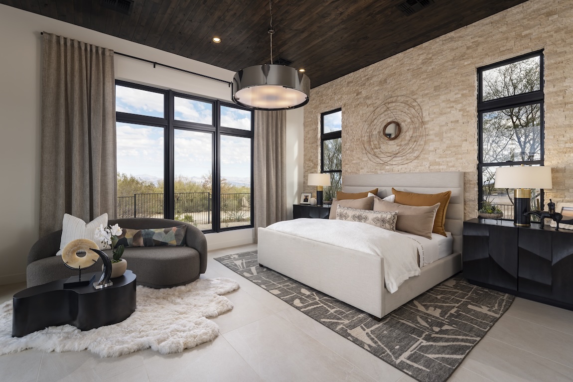 Luxe first-floor primary bedroom featuring ample natural lighting and cozy seating area